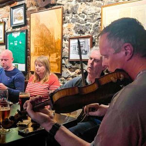 Angled shot of a man playing the fiddle during a traditional Irish music session at Katie Dalys Limerick